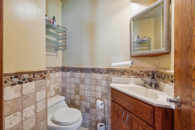 bathroom featuring vanity, toilet, and tile walls