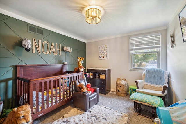 carpeted bedroom featuring crown molding, a crib, and an inviting chandelier