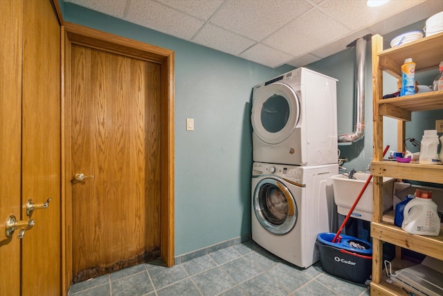 laundry room featuring tile patterned floors, stacked washer / drying machine, and sink