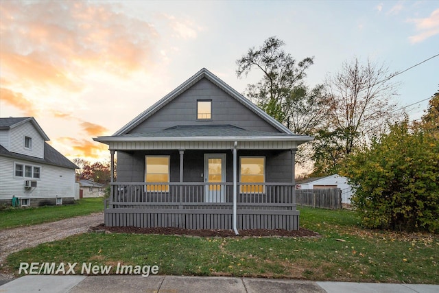 bungalow-style home featuring cooling unit, covered porch, and a yard