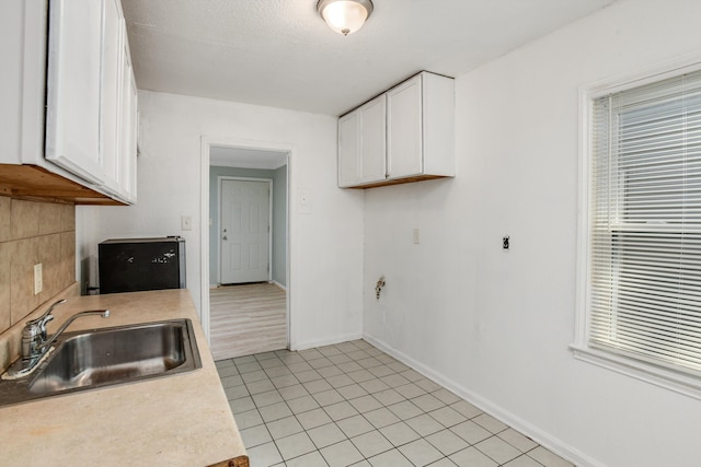 kitchen with light tile patterned floors, white cabinetry, and sink