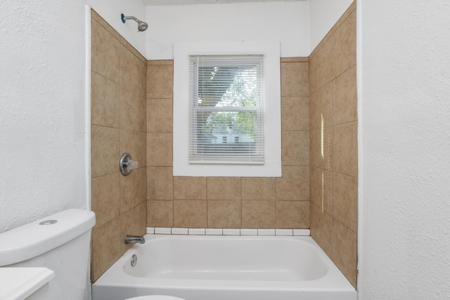 bathroom with toilet and tiled shower / bath