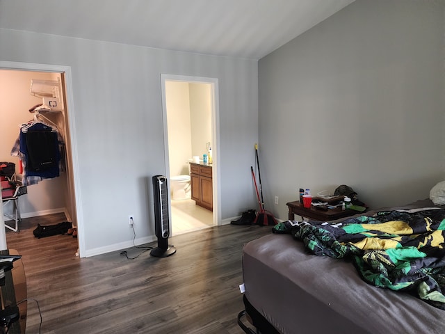 bedroom with a walk in closet, dark hardwood / wood-style flooring, ensuite bath, and a closet