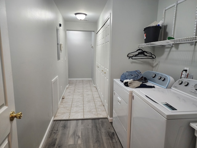 clothes washing area featuring washing machine and dryer and light hardwood / wood-style flooring