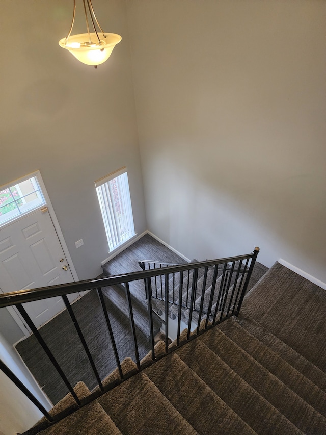 stairway with carpet flooring and a high ceiling