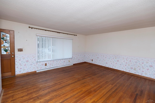 spare room featuring a textured ceiling, dark wood-type flooring, and a baseboard radiator