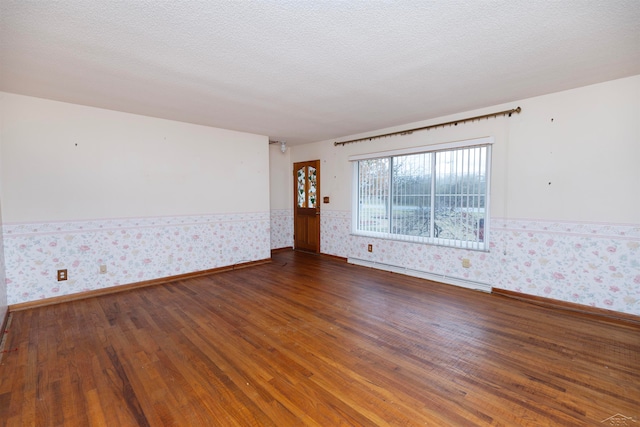 empty room featuring a textured ceiling, dark hardwood / wood-style floors, and a baseboard radiator