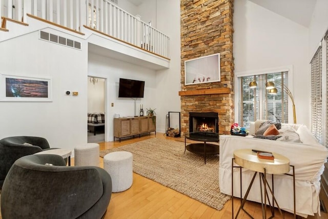 living room featuring a stone fireplace, hardwood / wood-style floors, and high vaulted ceiling