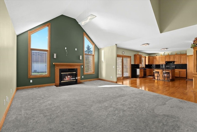 living room featuring light wood-type flooring, vaulted ceiling, and plenty of natural light