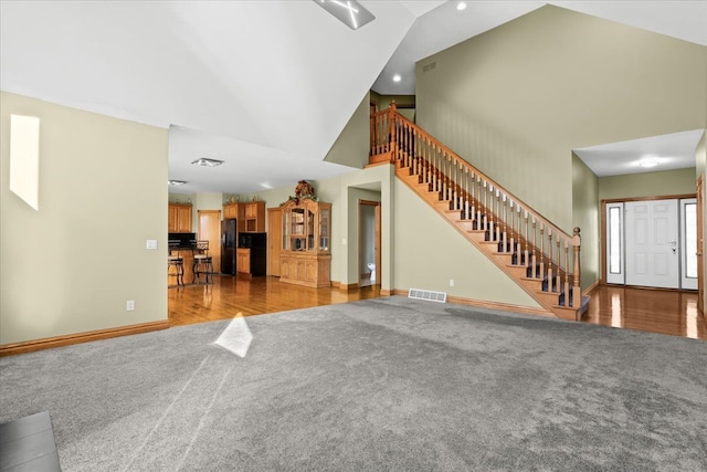 unfurnished living room with hardwood / wood-style flooring and high vaulted ceiling