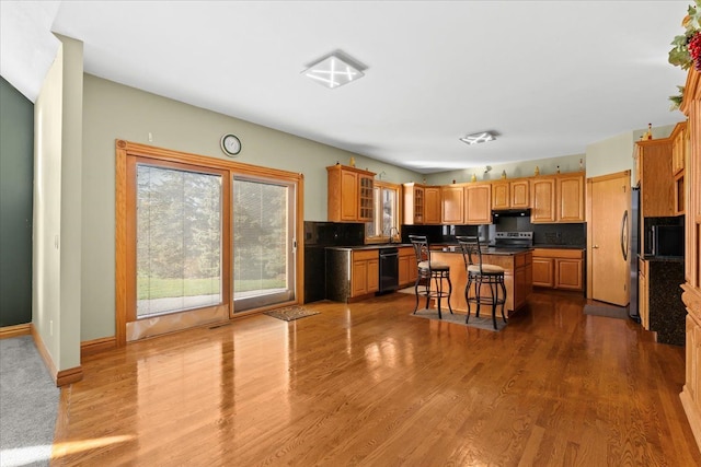 kitchen with a breakfast bar, light wood-type flooring, a center island, and stainless steel appliances