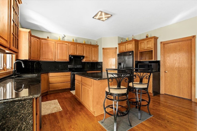 kitchen featuring dark hardwood / wood-style flooring, range hood, a kitchen island, and black appliances