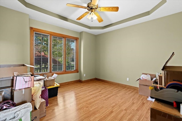 sitting room featuring ceiling fan, a raised ceiling, and light wood-type flooring