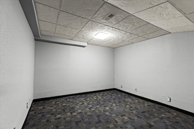 carpeted empty room with a paneled ceiling