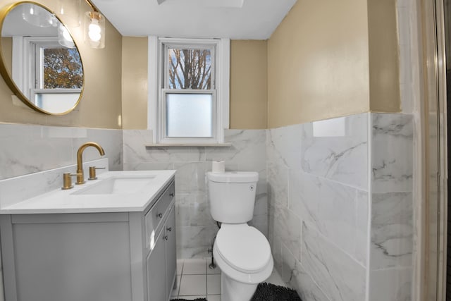 bathroom with tile patterned flooring, vanity, tile walls, and toilet