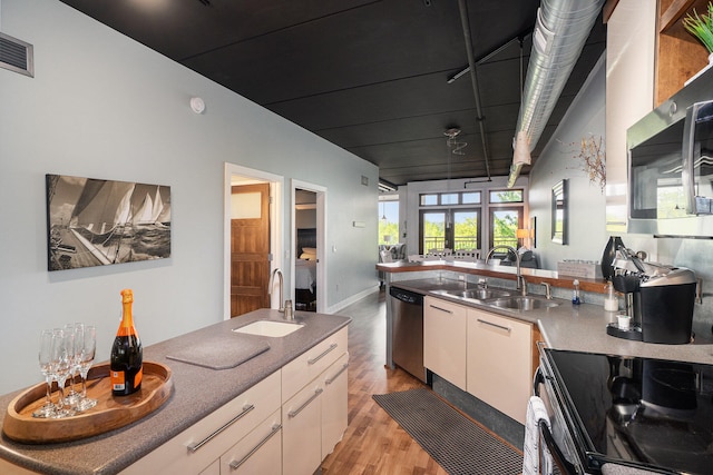 kitchen featuring sink, dishwasher, electric range oven, light hardwood / wood-style flooring, and kitchen peninsula