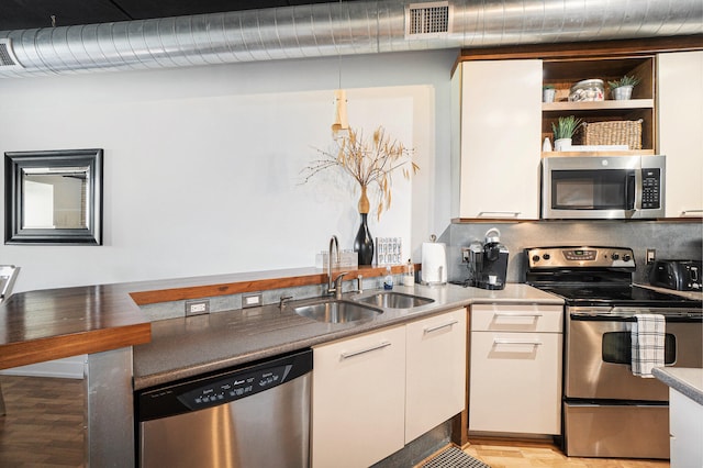 kitchen featuring appliances with stainless steel finishes, light hardwood / wood-style floors, white cabinetry, and sink