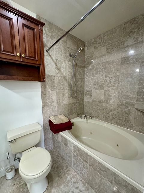 bathroom featuring tiled shower / bath combo and toilet