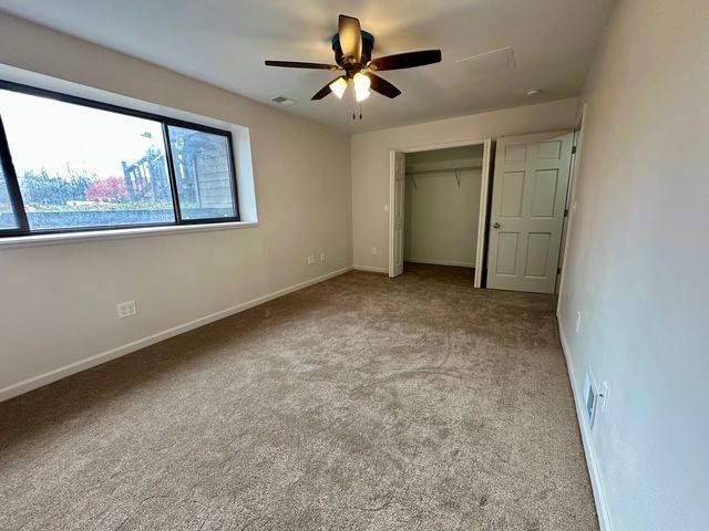 unfurnished bedroom featuring ceiling fan, a closet, and light colored carpet