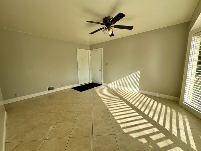 unfurnished bedroom featuring ceiling fan, light tile patterned floors, and multiple windows