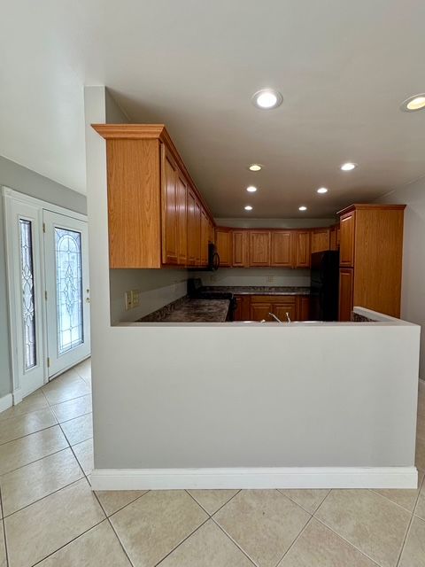 kitchen featuring black appliances, kitchen peninsula, and light tile patterned floors