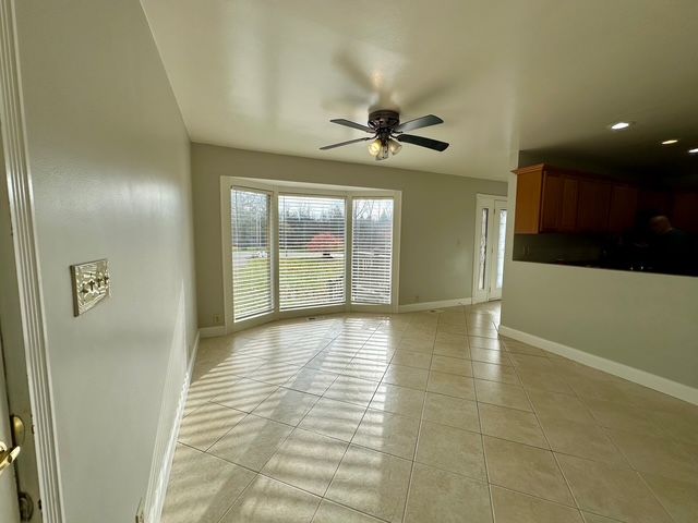 empty room with ceiling fan and light tile patterned flooring