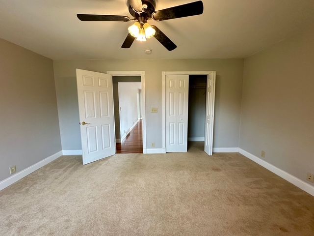 unfurnished bedroom with carpet flooring, ceiling fan, and a closet