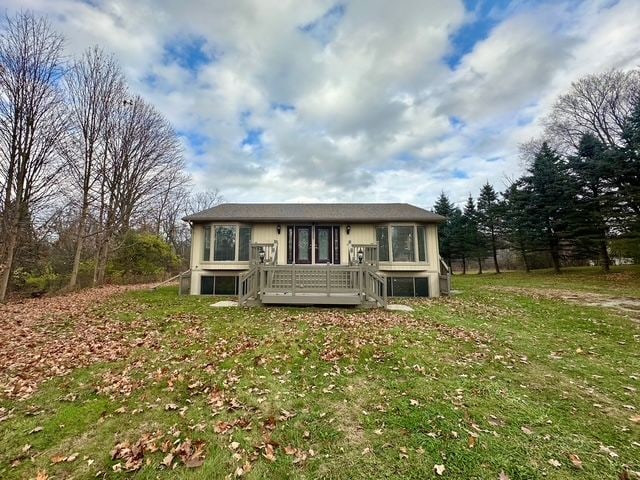 view of front of property with a deck and a front lawn