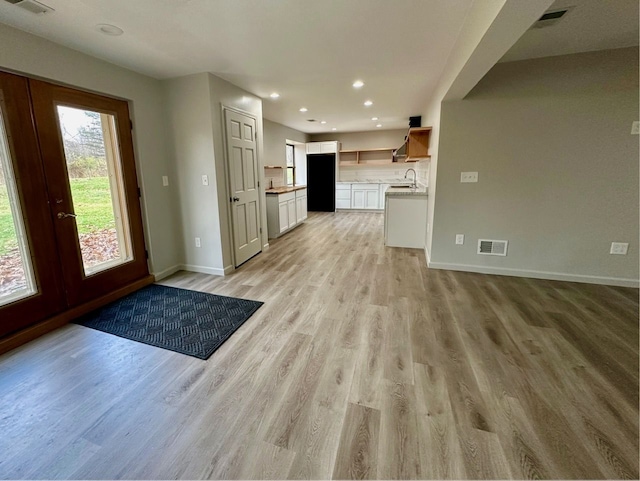 kitchen with white cabinets, light wood-type flooring, and sink