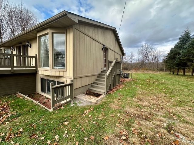 view of side of property with a yard, a wooden deck, and central air condition unit