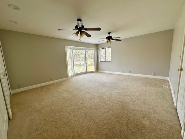 carpeted empty room featuring ceiling fan