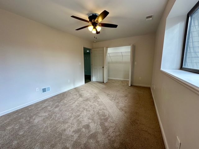 unfurnished bedroom featuring ceiling fan, a closet, carpet floors, and multiple windows