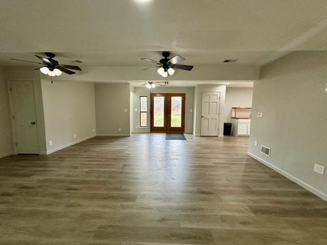 unfurnished living room with ceiling fan, wood-type flooring, and french doors