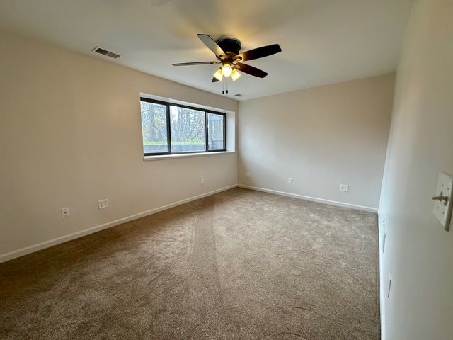 carpeted empty room featuring ceiling fan