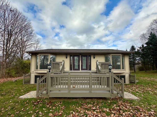 rear view of property featuring french doors, a deck, and a lawn