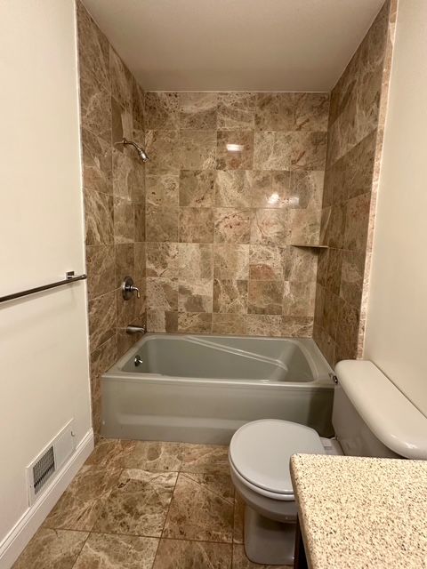 full bathroom featuring tiled shower / bath combo, toilet, and vanity