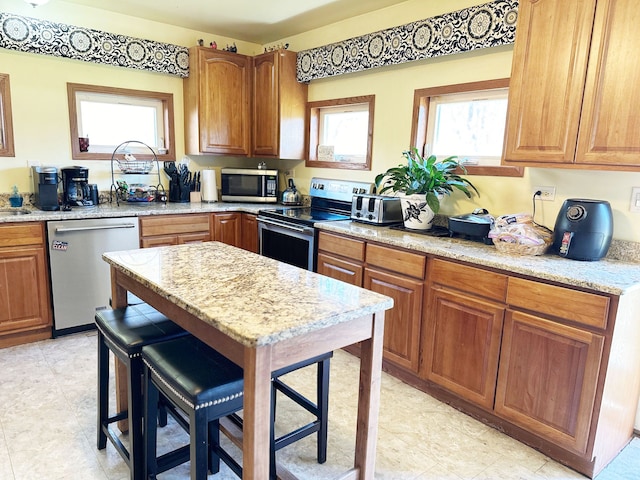 kitchen with a breakfast bar, light stone counters, and appliances with stainless steel finishes