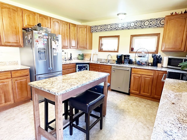 kitchen with wine cooler, stainless steel appliances, light stone counters, and sink