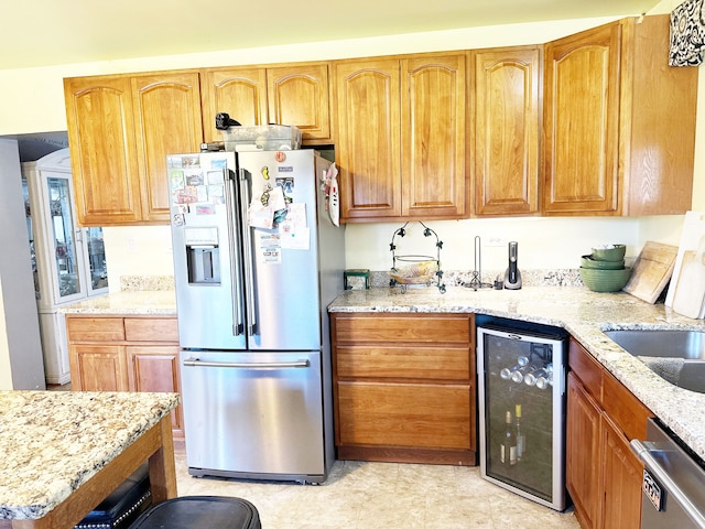 kitchen with wine cooler, light stone counters, sink, and stainless steel appliances