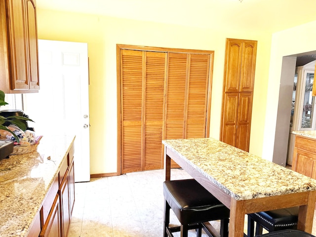 kitchen with a center island, light stone counters, and a breakfast bar area