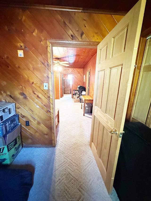 hall featuring wooden walls, carpet floors, and wooden ceiling