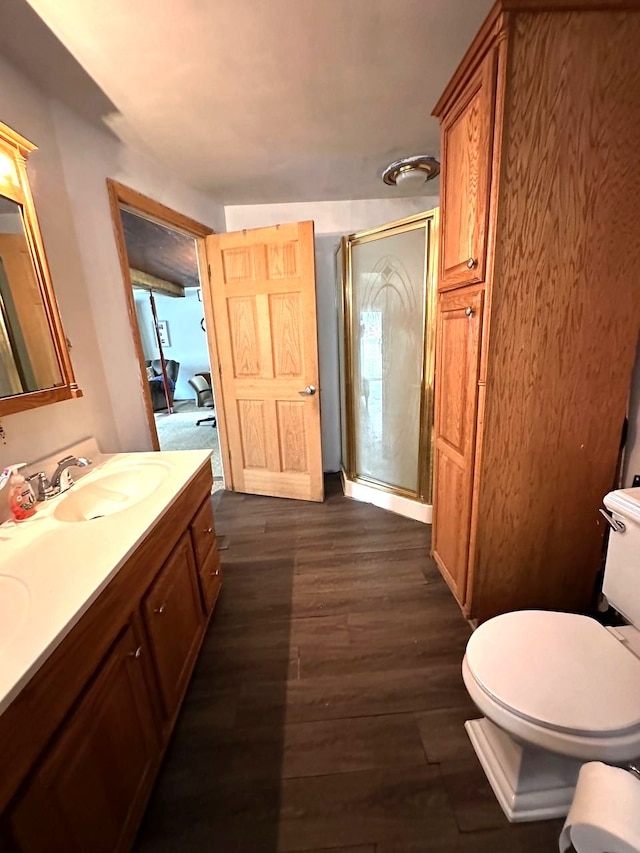 bathroom with hardwood / wood-style floors, vanity, toilet, and a shower with shower door