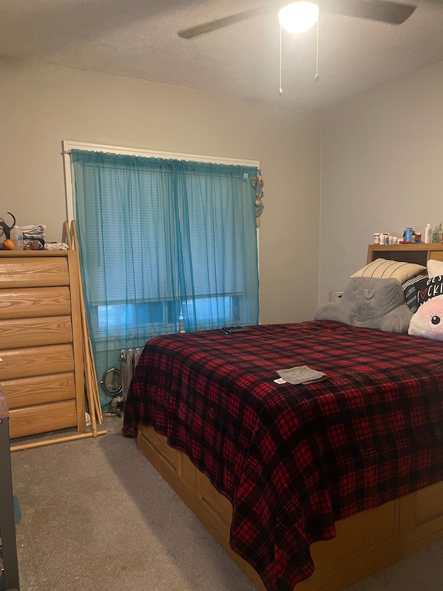 carpeted bedroom featuring radiator heating unit, a textured ceiling, and ceiling fan