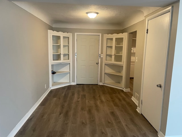 hall with a textured ceiling and dark hardwood / wood-style floors