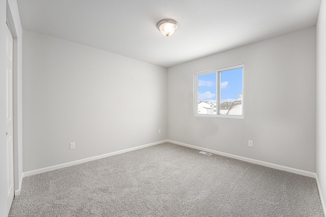 spare room featuring carpet floors, visible vents, and baseboards