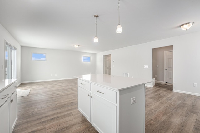 kitchen featuring light wood-style flooring, a kitchen island, light countertops, and decorative light fixtures