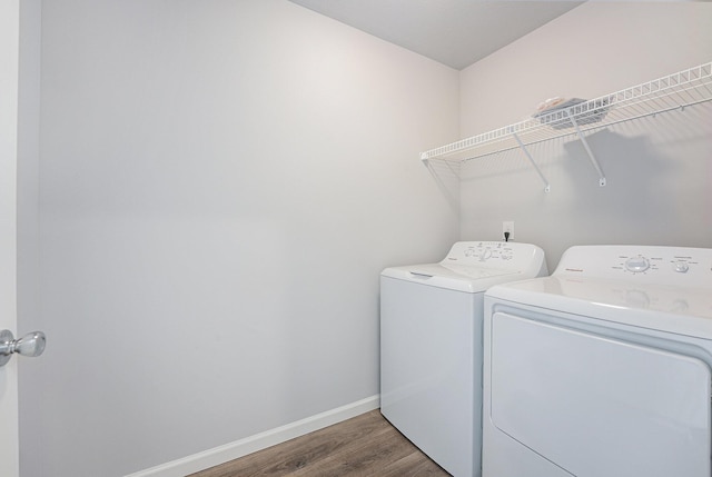 washroom featuring laundry area, baseboards, wood finished floors, and washing machine and clothes dryer