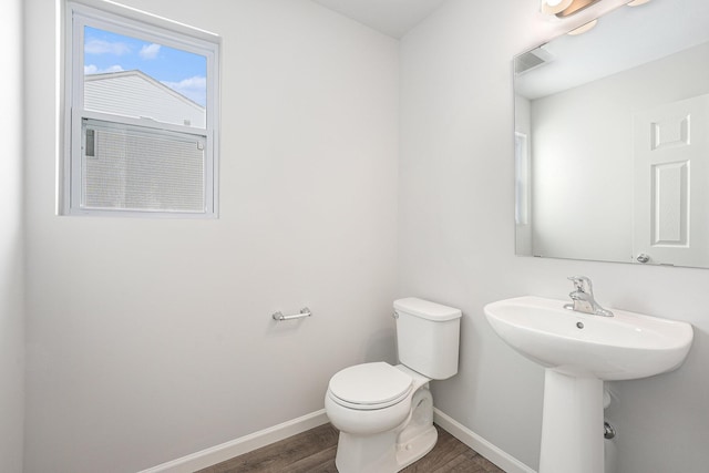 bathroom featuring toilet, visible vents, baseboards, and wood finished floors