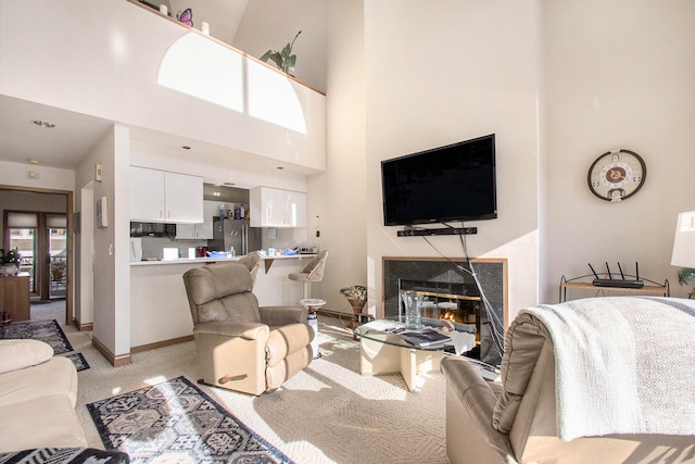 carpeted living room with a fireplace and a towering ceiling