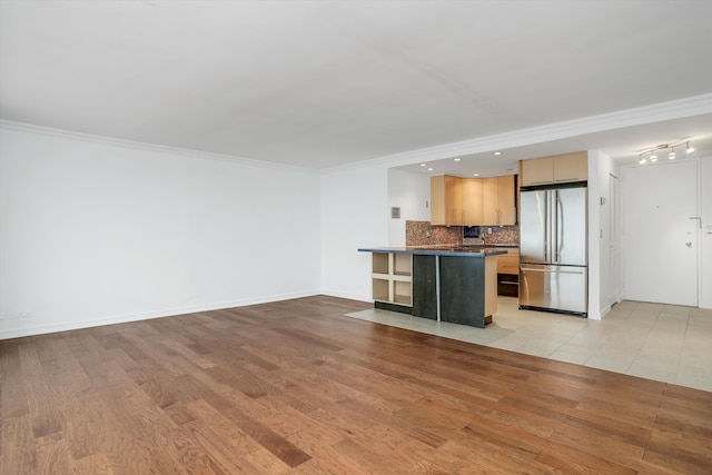 kitchen featuring crown molding, light hardwood / wood-style flooring, stainless steel refrigerator, backsplash, and light brown cabinetry